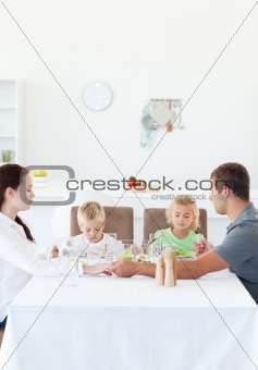 Family holding their hands while praying before eating a salad