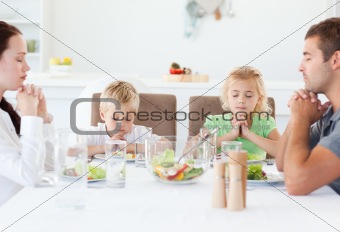 Portrait of a family praying together during the lunch