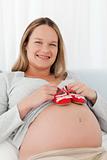 Pregnant woman putting baby shoes on her belly