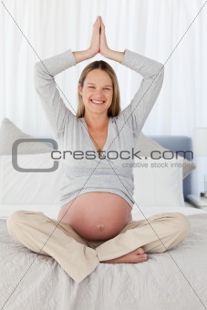 Cute future mom doing yoga on a bed 