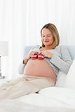 Pretty pregnant woman having  baby shoes on her belly resting 