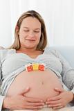 Cute pregnant woman with mom letters on her belly