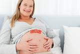 Blond pregnant woman with mom letters on her belly lying 