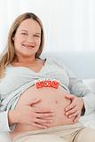 Cheerful young woman with mom letters on her belly
