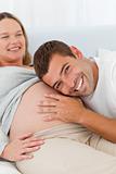 Happy man listening the belly of his pregnant wife
