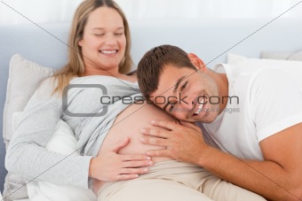 Happy future dad listening the belly of his pregnant wife