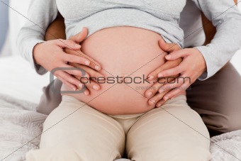 Close up of a couple touching the belly of the pregnant woman 