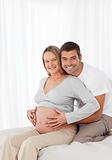 Cute pregnant woman touching her belly with her husband 