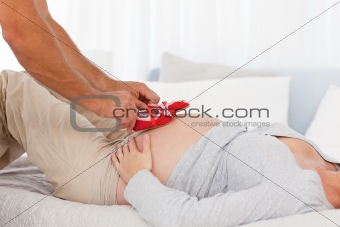 Affectionate man putting baby shoes on his wife's belly