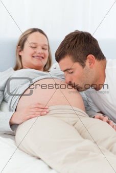 Proud future dad kissing the belly of his wife