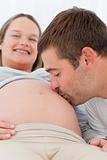 Happy man kissing the belly of his pregnant wife while relaxing