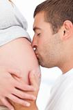 Future father kissing the belly of his pregnant wife