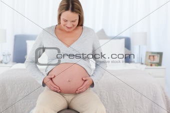 Joyful pregnant woman in her bedroom smiling at the camera