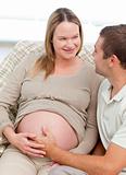 Lovely pregnant woman touching her belly with her husband 