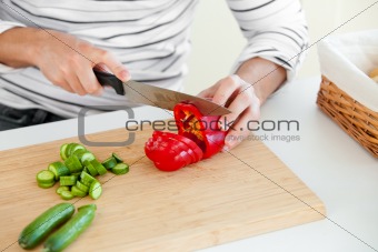 Close-up of a young man cutting vegetables in the kitchen