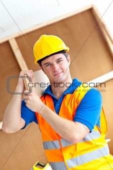 Self-assured young male worker with a yellow helmet carrying a w