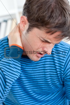 Caucasian man having a neckache in the living-room