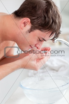 Positive caucasian man spraying water on his face after shaving 