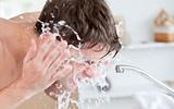 Bright caucasian man spraying water on his face after shaving in