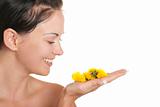 Smiling woman holds yellow flowers on palm