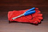 Red gloves and blue chisels on dark wooden floor