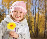 Portrait of smiling little girl with a yellow flower in the autumn forest.
