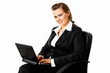 Smiling modern business woman sitting on  chair and using laptop
