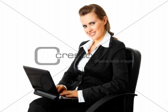 Smiling modern business woman sitting on  chair and using laptop
