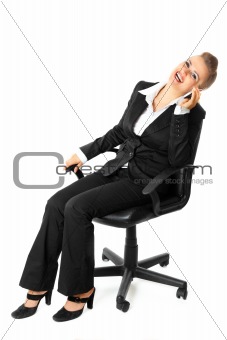 Successful modern business woman sitting on chair and talking on mobile phone
