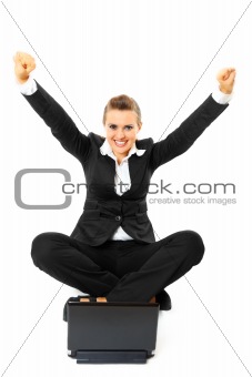 Excited modern business woman sitting on  floor with laptop and rejoicing her success 
