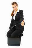 Sitting on floor with laptop smiling modern business woman showing thumbs up gesture

