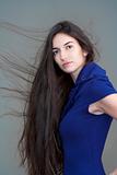 beautiful woman in blue dress with long brown hair flying - isolated on gray