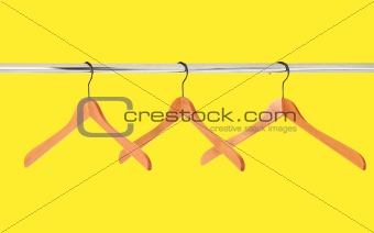 wooden coat hangers on a clothes rail isolated on yellow backgro