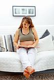 Beautiful pregnant woman sitting on sofa and reading book
