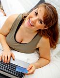 Smiling beautiful pregnant woman using credit card to shop from  internet
