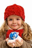 Little girl with a handful of snow and christmas bauble