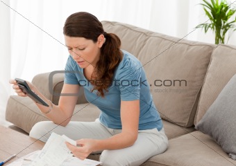 Nervous woman looking at her financial debts in the living room 