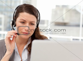 Concentrated businesswoman working on her laptop while calling