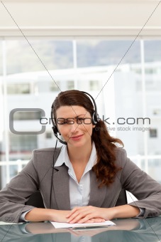 Cute businesswoman on the phone with earpiece sitting at a table