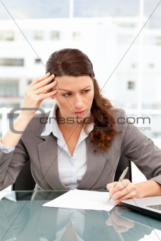 Concentrated businesswoman taking notes while working on her lap