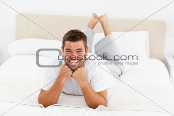 Handsome man laughing lying on his bed 