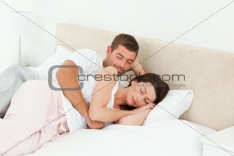 Passionate man looking at his girlfriend sleeping peacefully 