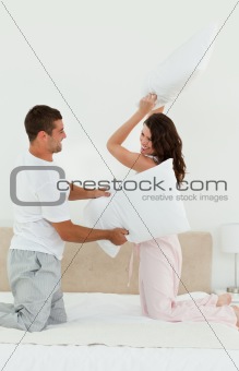 Lovely couple doing a pillow fight on their bed 
