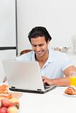 Cheerful man working on his laptop during snack time