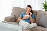 Attractive woman watching television and eating pop corn on the 