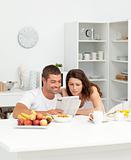 Happy couple reading the newspaper in the kitchen 