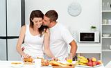 Affectionate man kissing his girlfriend while cutting bread for 