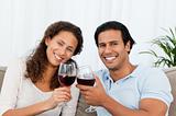 Happy couple drinking red wine sitting on the sofa