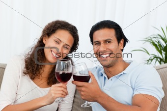 Happy couple drinking red wine sitting on the sofa