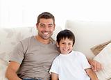 Portrait of adorable father and son sitting on the sofa 